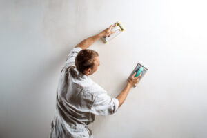 Professional worker grinding white wall with sandpaper. Copy space.